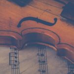 Artistic close-up of a violin on sheet music, highlighting musical elegance.